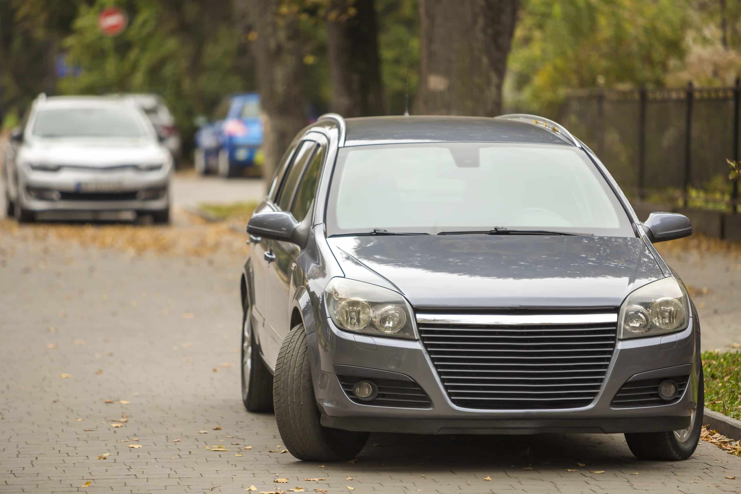 gray shiny car parked in quiet area on asphalt road on blurred b