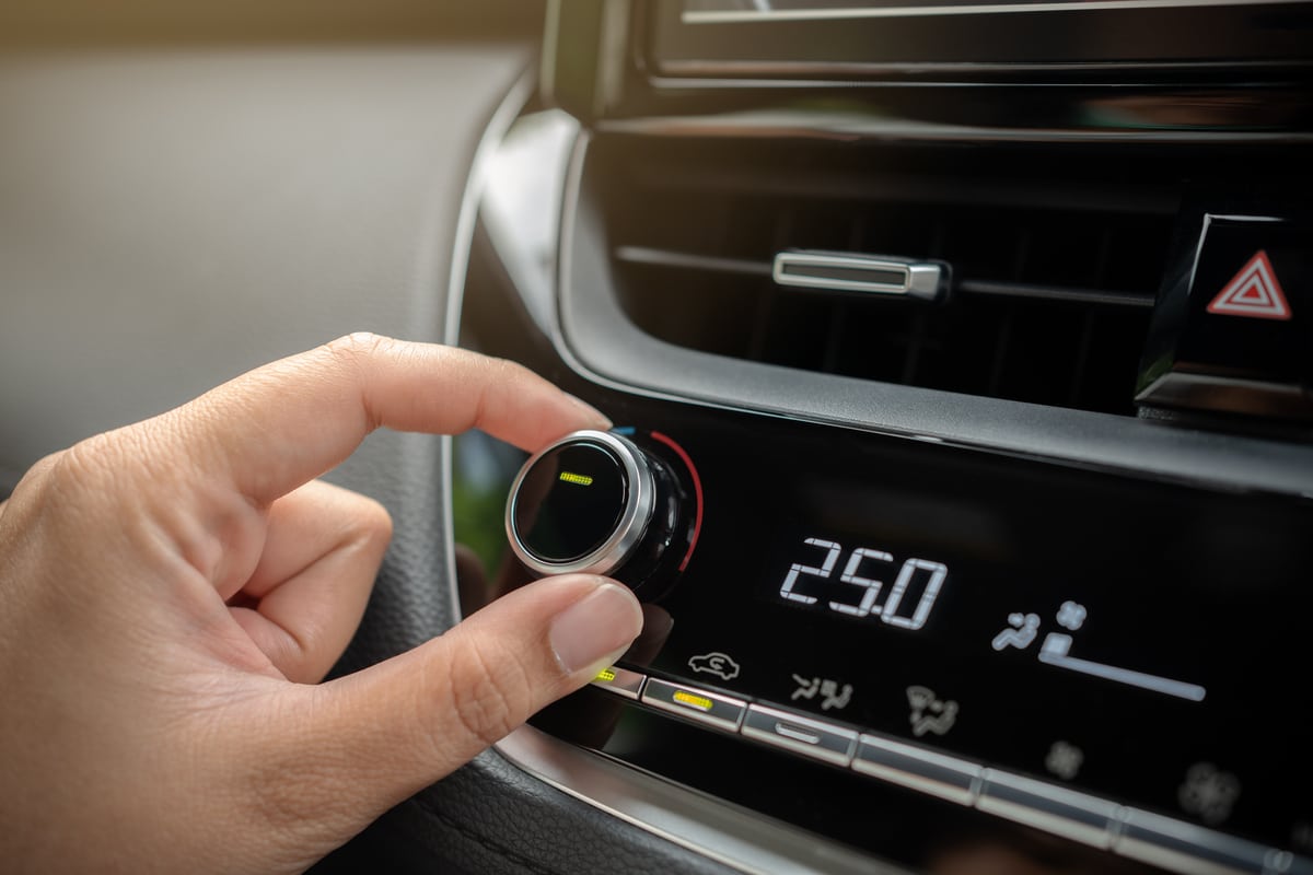 driver adjusting car air conditioner system at interior panel